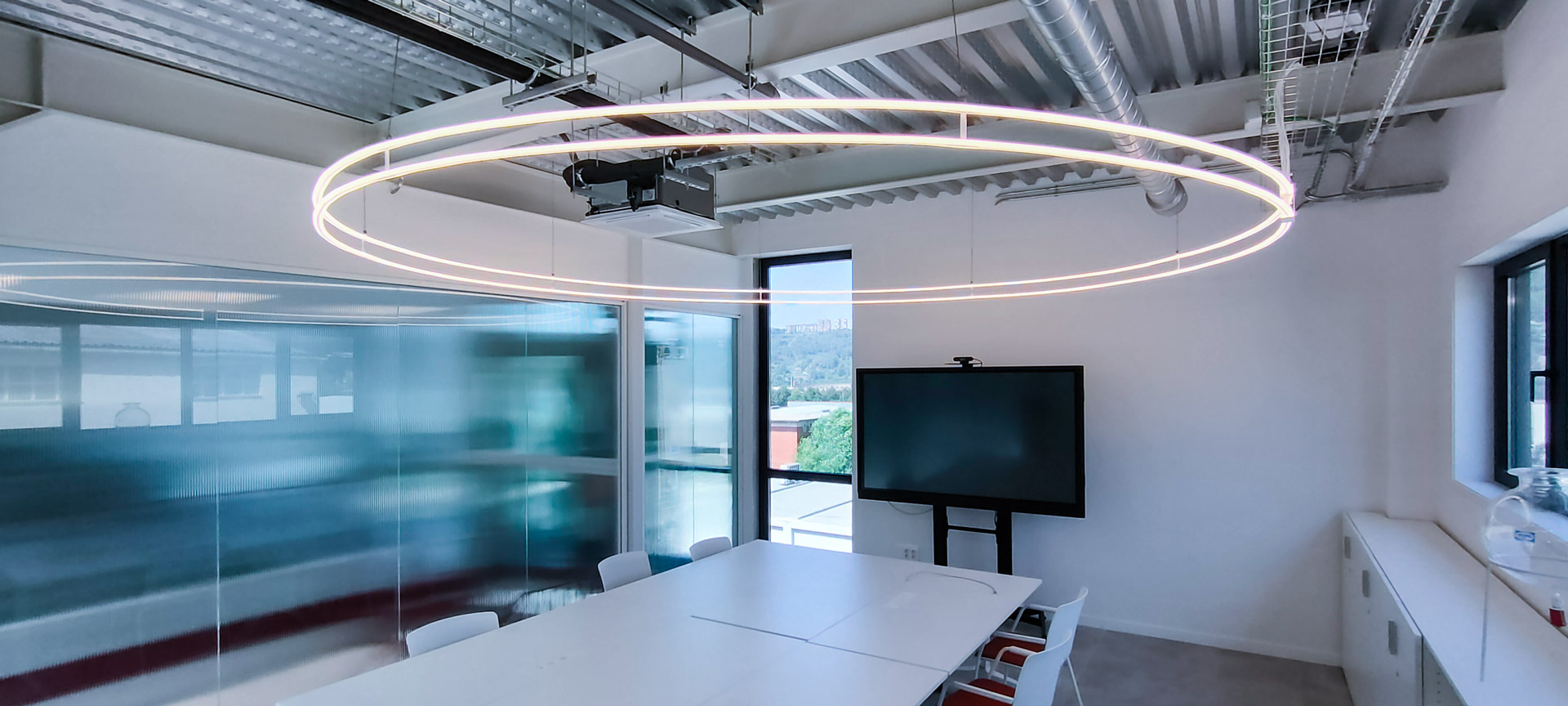 Iluminación LED circular en sala de reuniones de Lasenor, diseño industrial moderno realizado por LUXES.