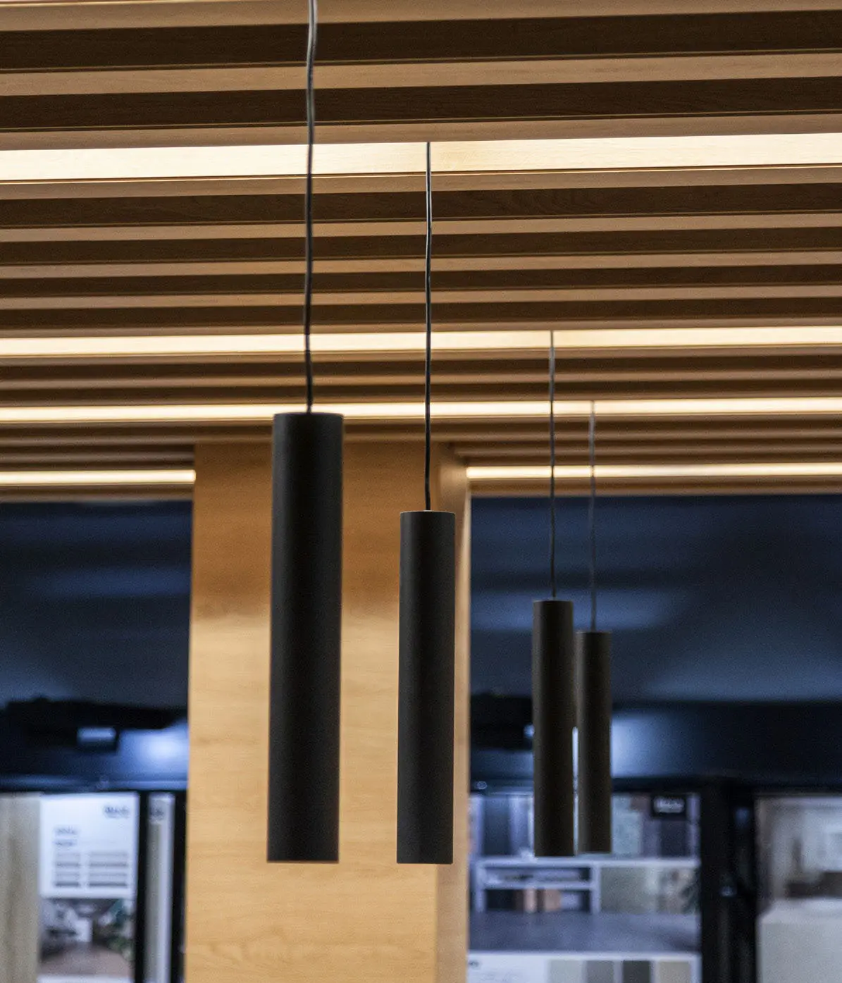 Luminarias LED cilíndricas suspendidas en techo de madera en oficinas Andorra, diseño lumínico de Luxes.