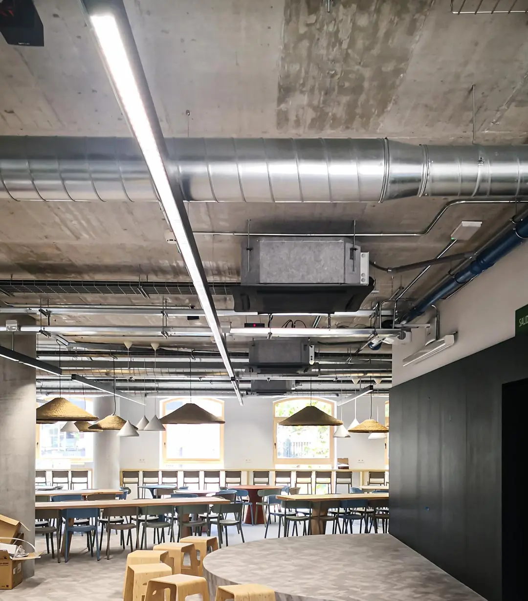 Iluminación LED lineal en zona común de oficinas KNEM, proyecto lumínico moderno de Luxes.