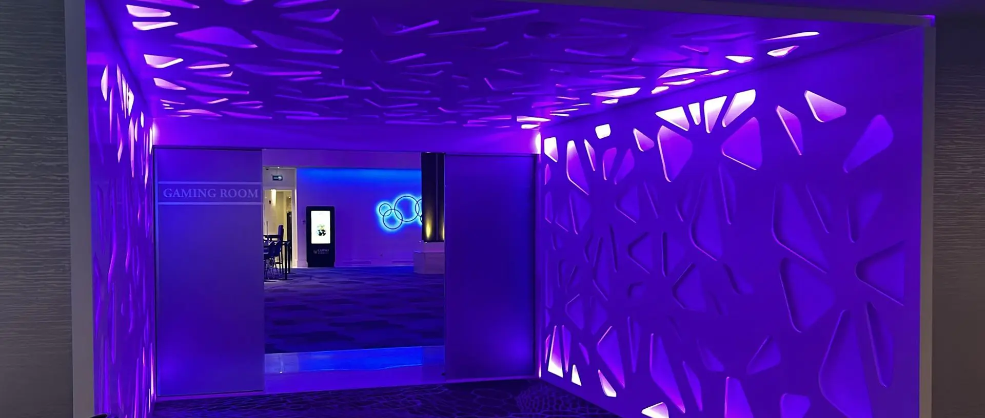 Entrada al Casino Marbella con iluminación arquitectónica LED y paredes retroiluminadas de diseño orgánico.
